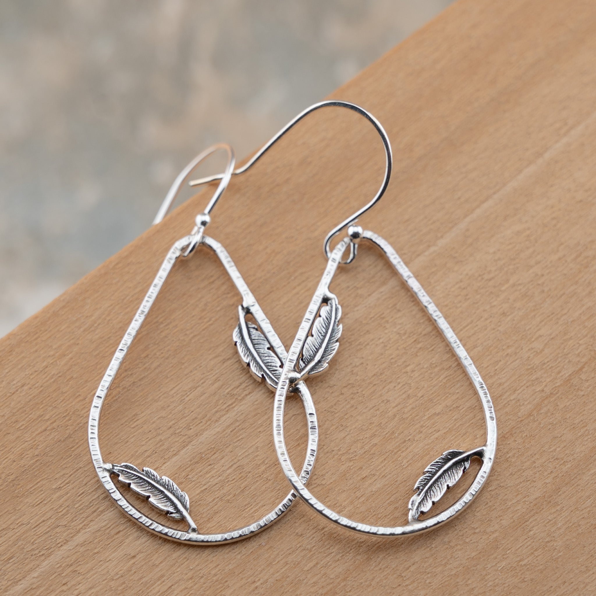 Sterling silver teardrop hoop earrings with dainty feather accents